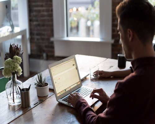 person working on a laptop beside a bright window