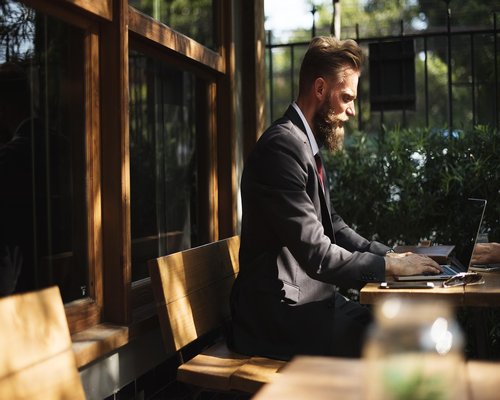 person working on a laptop beside a bright window